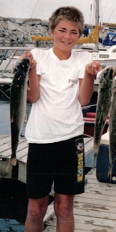 William in his pre-teens, Standing on a dock, Awkwardly holding up two large fish he'd caught